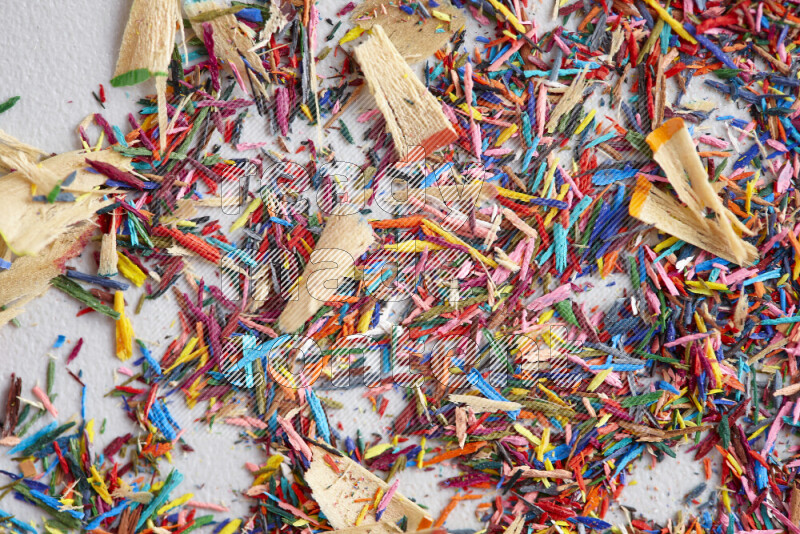 This image showcases a vibrant multicolored pencil shavings scattered on grey background