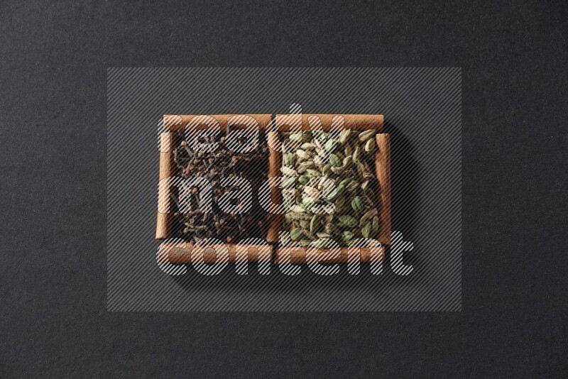 2 squares of cinnamon sticks full of cardamom and cloves on black flooring