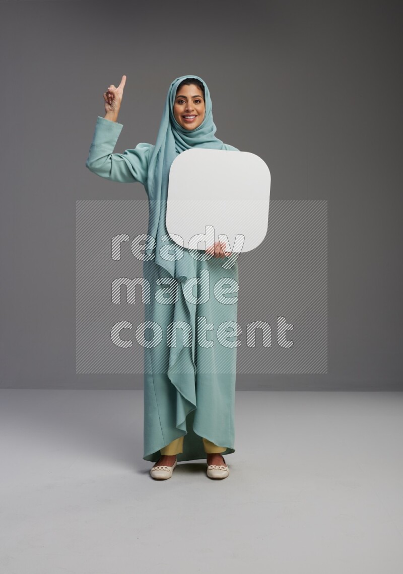 Saudi Woman wearing Abaya standing holding social media sign on Gray background