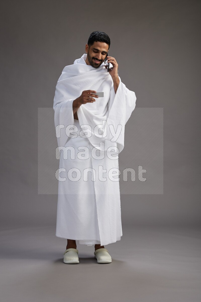 A man wearing Ehram Standing holding ATM card on gray background