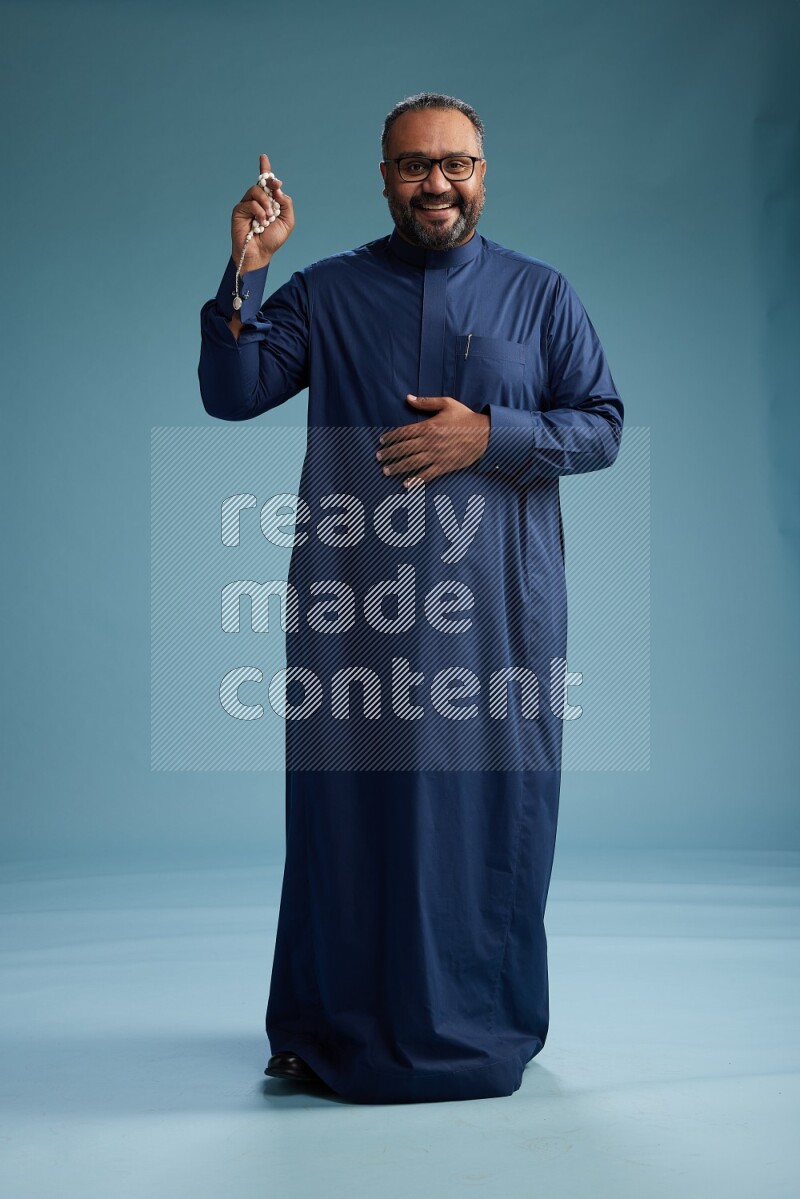 Saudi Man without shimag Standing Interacting with the camera on blue background