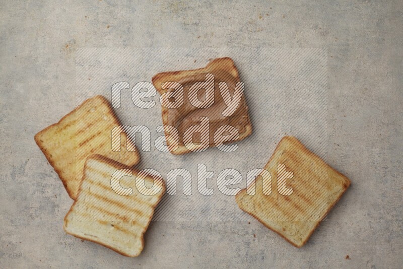 Creamy peanut butter on a toasted white toast and toasted white toast slices on a light blue textured background