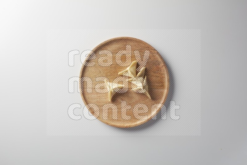 Four Sambosas on a wooden round plate on a white background
