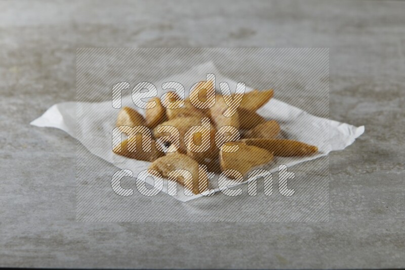 wedges potato on parchment paper on grey textured counter top