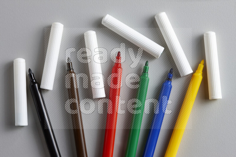 An arrangement of coloring pens in different colors on grey background