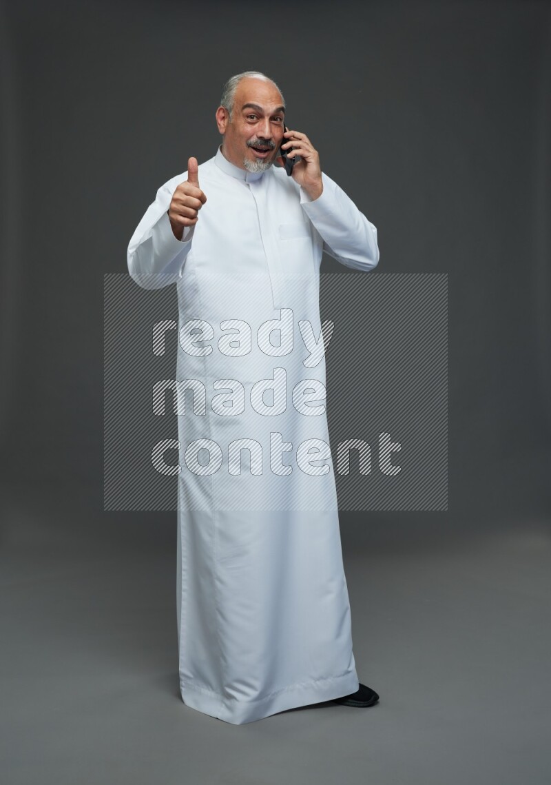 Saudi man without shomag Standing talking on phone on gray background