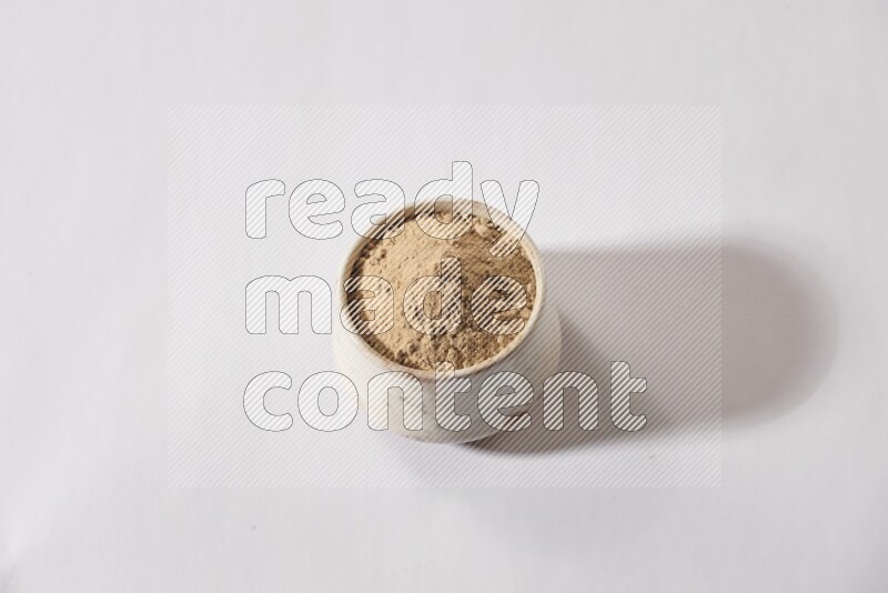 A beige pottery bowl full of garlic powder on a white flooring