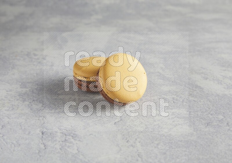 45º Shot of two Yellow and Brown Chai Latte macarons r on white  marble background