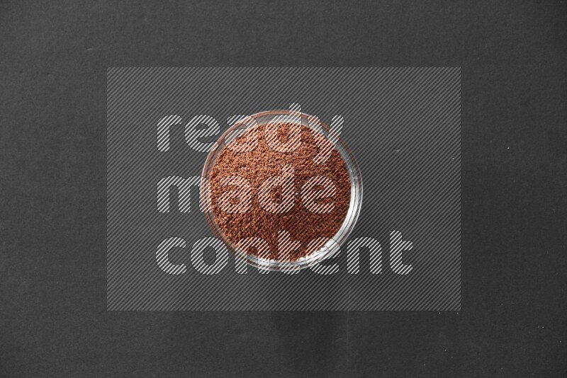 A glass bowl full of garden cress on black flooring