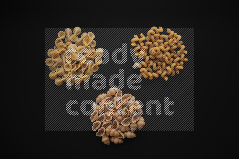Different pasta types in bunches on black background