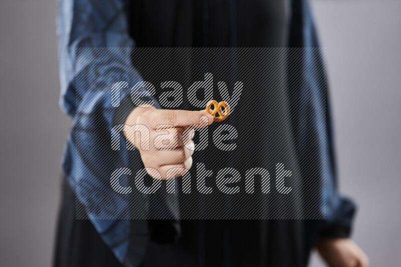 Woman in abaya holding different kinds of snacks in different positions