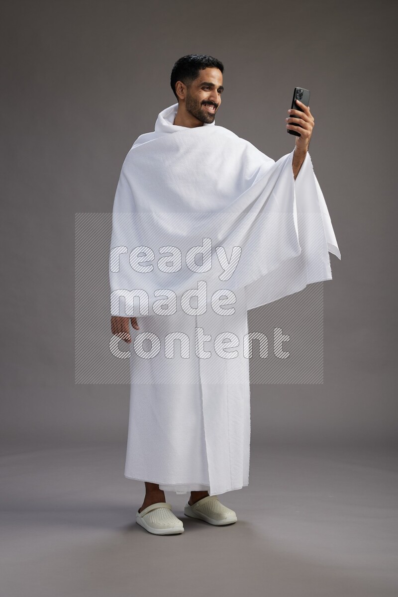 A man wearing Ehram Standing taking selfie on gray background