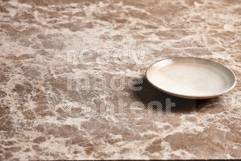A beige pottery plate on beige marble background