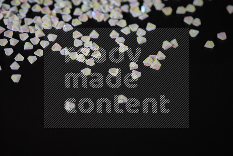 Colorful plastic shards for decoration scattered on a black background