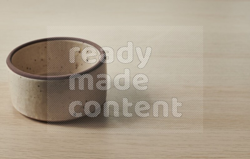 A beige pottery oven bowl on light wooden background