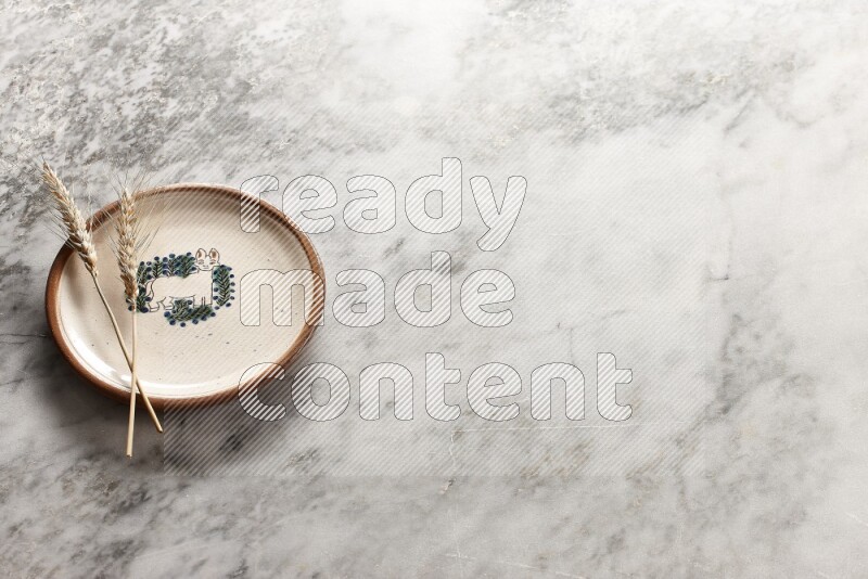 Wheat stalks on decorative pottery plate on grey marble background
