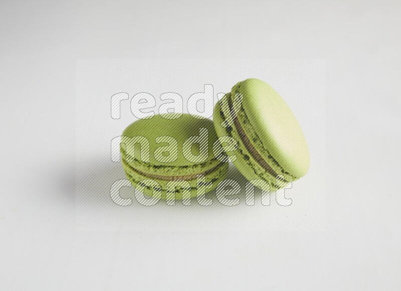 45º Shot of two Green Pistachio macarons on white background
