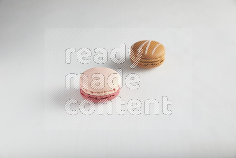 45º Shot of of two assorted Brown Irish Cream, and Pink Litchi Raspberry macarons on white background
