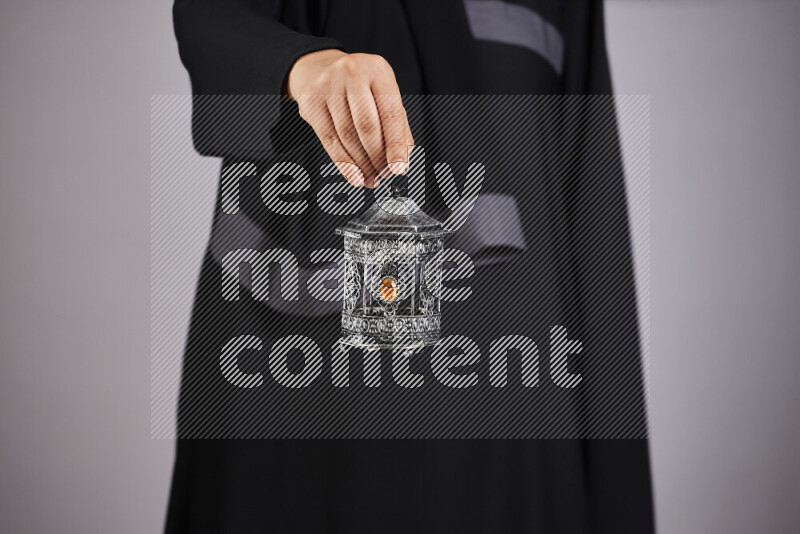A woman in black abaya holding different ramadan lanterns in different positions