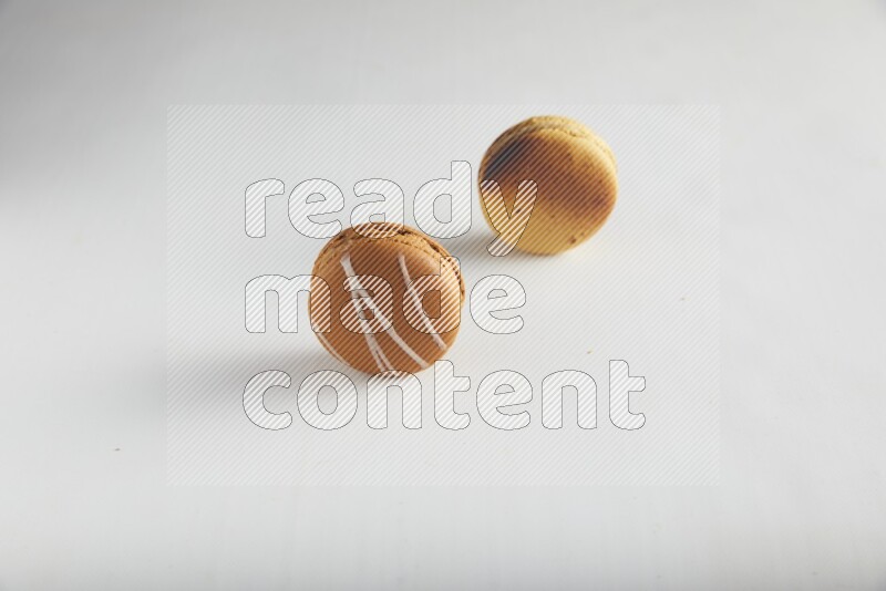 45º Shot of of two assorted Brown Irish Cream, and Yellow Crème Brulée macarons on white background