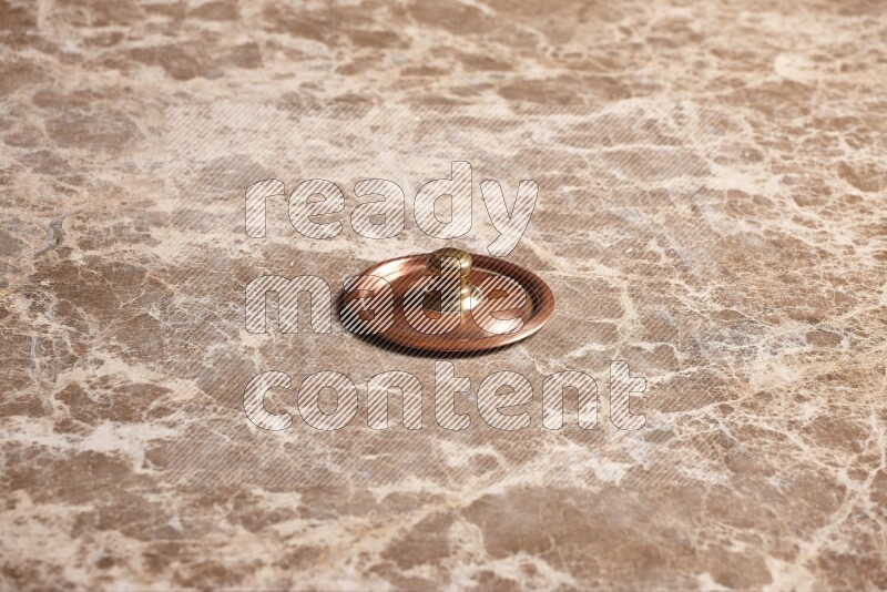 A small copper pot lid on beige marble background