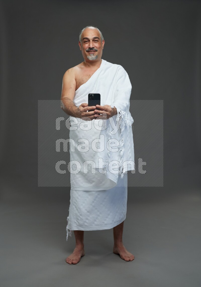 A man wearing Ehram Standing taking selfie on gray background