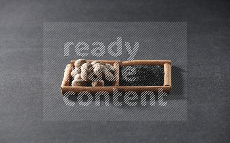 مربعان من أعواد القرفة ممتلئان بحبة البركة السوداء وجوزة الطيب علي خلفية سوداء