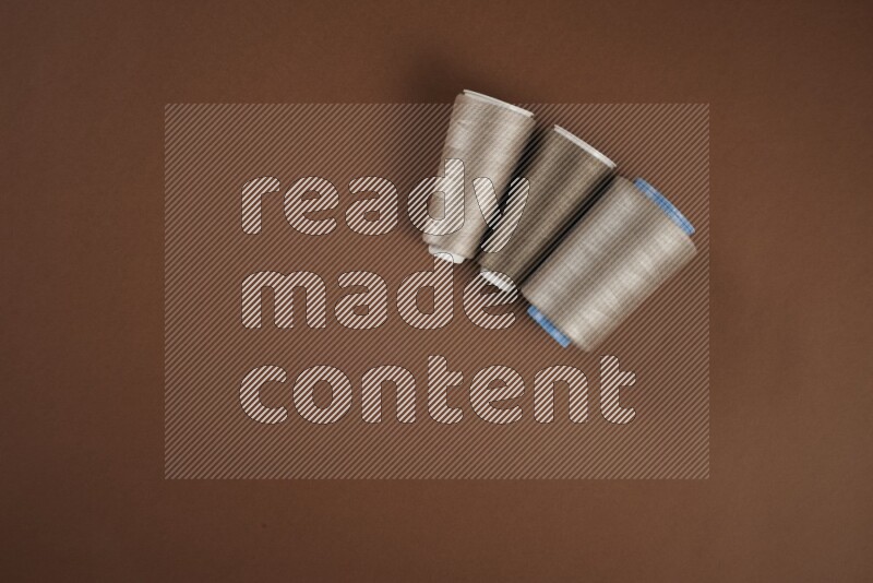 A brown collection of sewing and tailoring tools arranged on a brown background