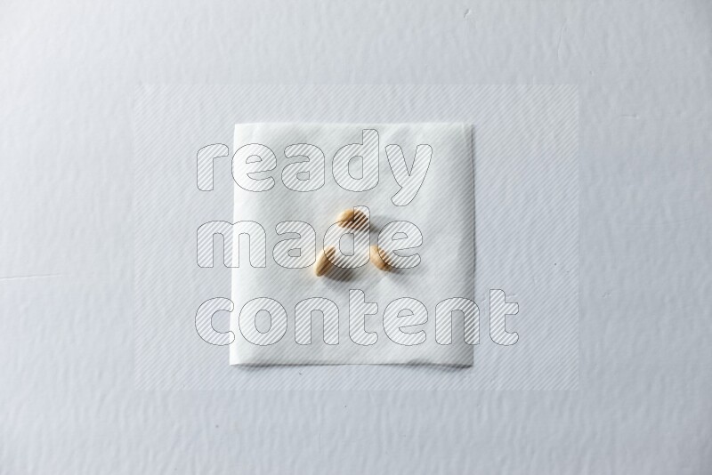 3 peeled peanuts on a piece of paper on a white background in different angles