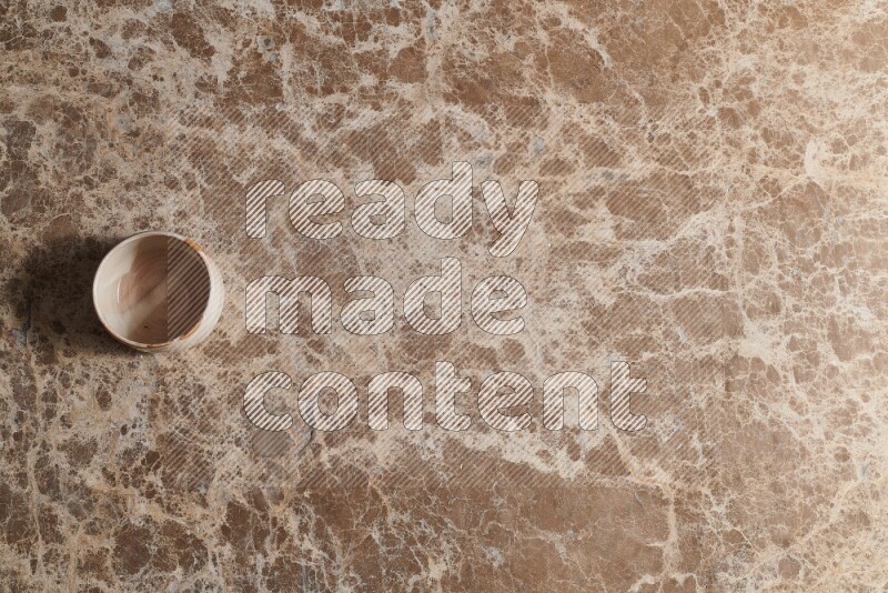 A multicolored pottery bowl on beige marble background