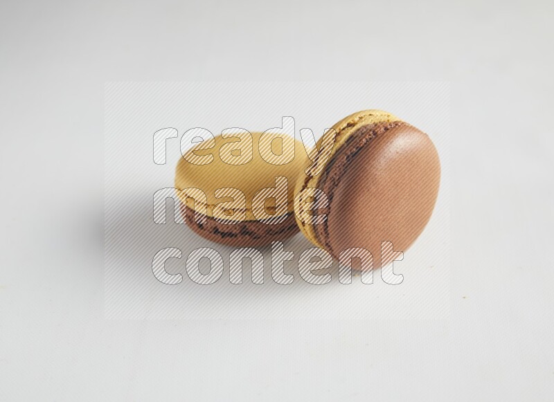 45º Shot of two Yellow and Brown Chai Latte macarons on white background