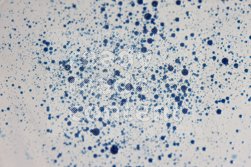 لقطات مقربة لقطرات ألوان مائية زرقاء على سطح الزيت على خلفية بيضاء