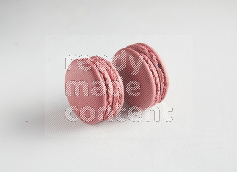 45º Shot of two Pink Raspberry macarons on white background