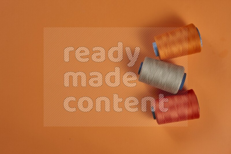 A brown collection of sewing and tailoring tools arranged on a orange background