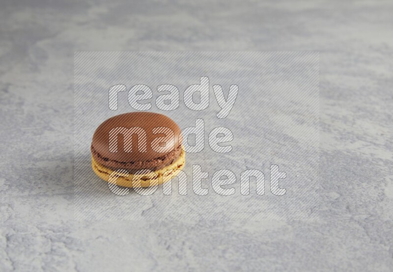 45º Shot of Yellow and Brown Chai Latte macaron on white  marble background