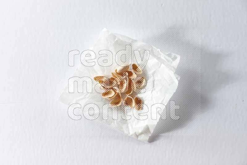Pistachio peels on a crumpled piece of paper on a white background in different angles