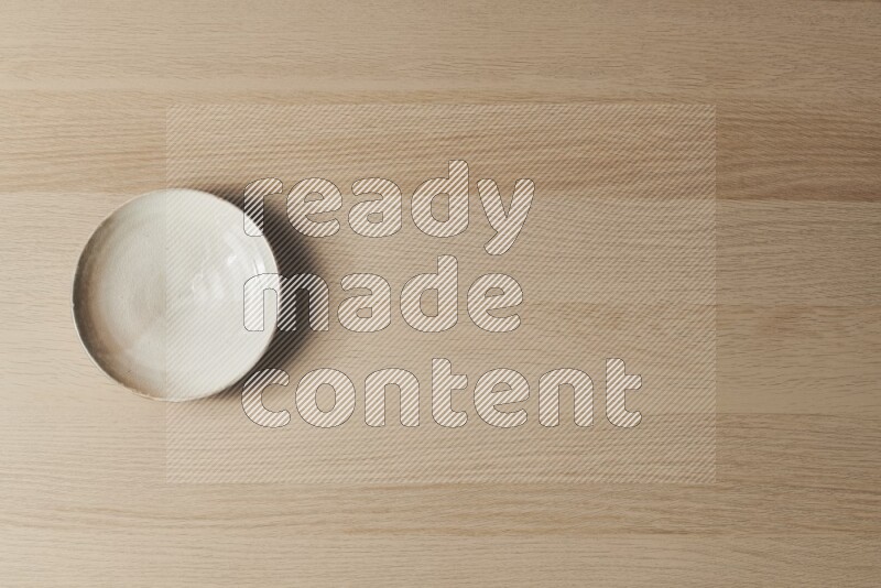 A beige pottery plate on light wooden background