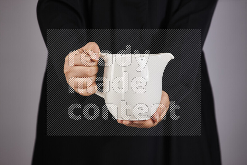 A woman in black abaya holding different pottery essentials in different positions