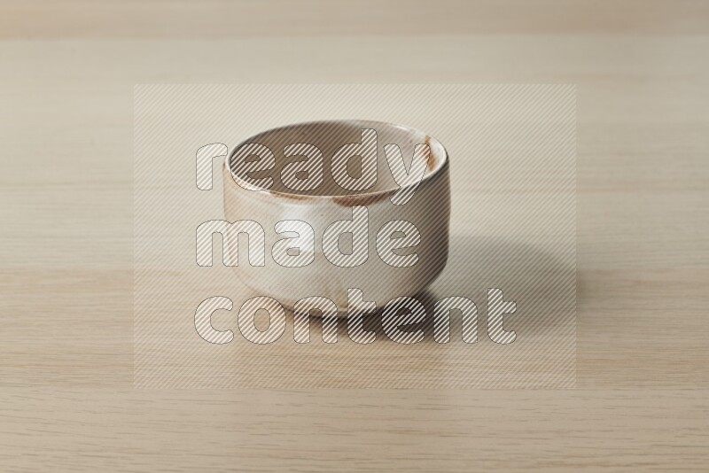 A beige pottery bowl on light wooden background
