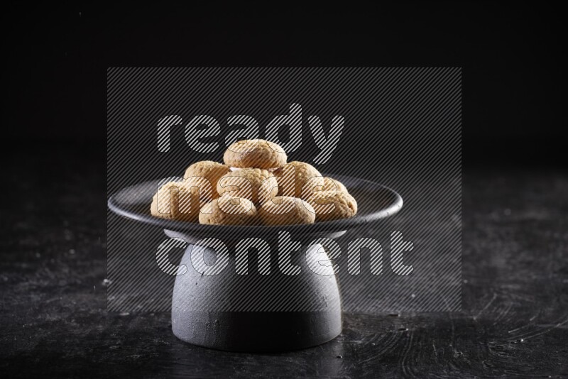 Kahk on a serving plate on a black background
