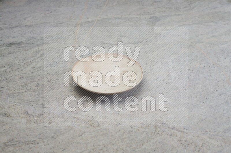 A beige pottery plate on grey marble background