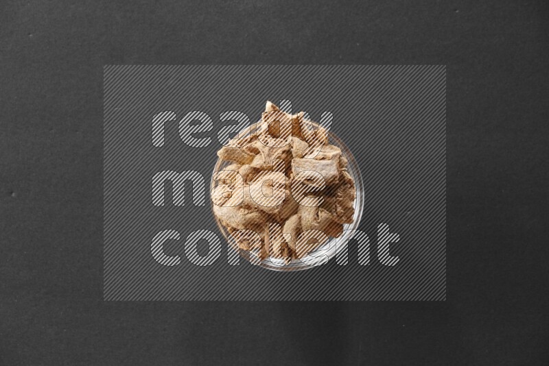 A glass bowl full of ginger on black flooring