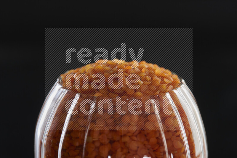 Lentils in a glass jar on black background
