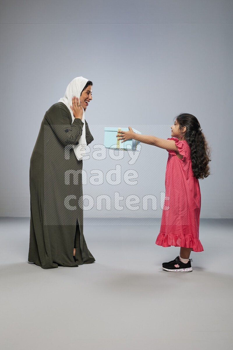 A girl giving a gift to her mother on gray background