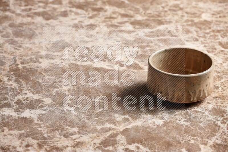 A beige pottery oven bowl on beige marble background