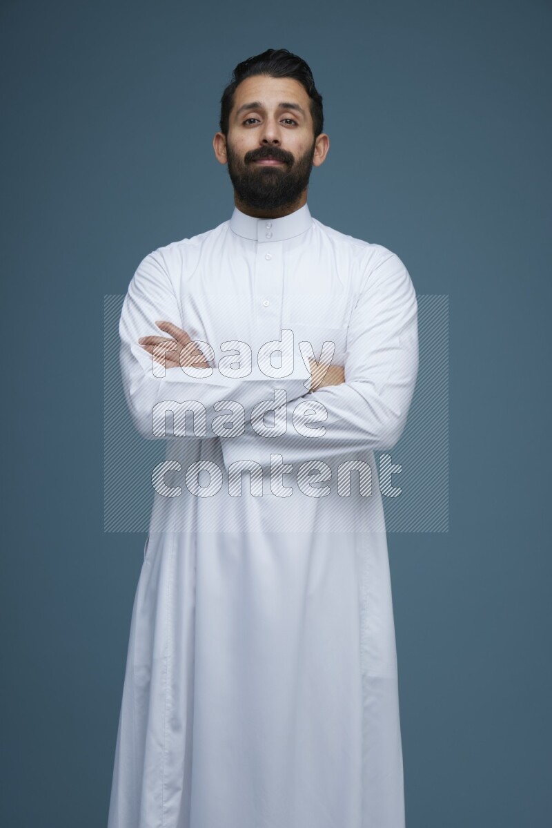 A man posing in a blue background wearing Saudi Thob