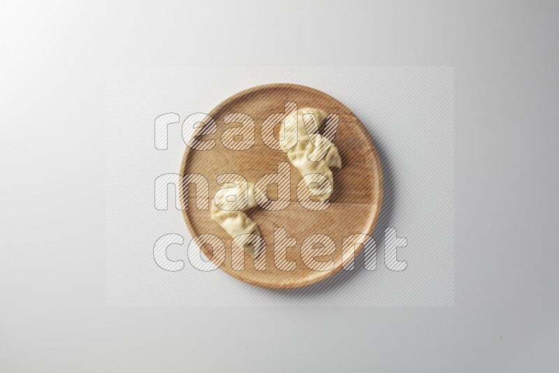 Five Sambosas on a wooden round plate on a white background