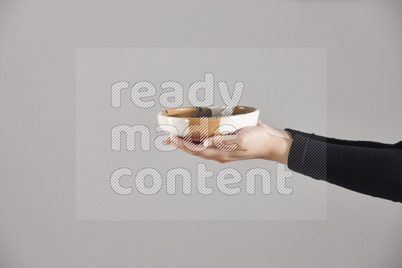 A woman in black abaya holding different pottery essentials in different positions