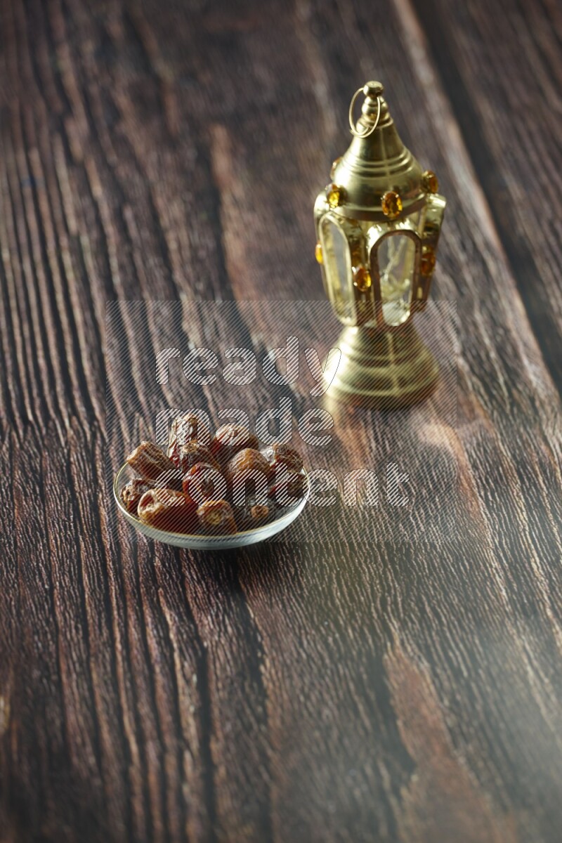 A golden lantern with different drinks, dates, nuts, prayer beads and quran on brown wooden background