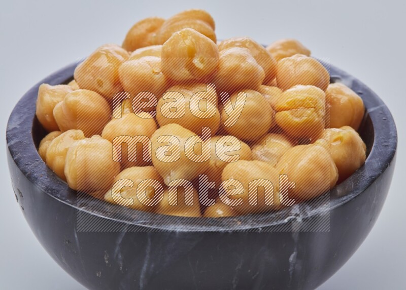 Close up shot of boiled chickpeas in a container on white background